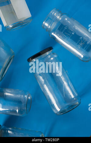 Transparent glass jars with lids isolated on blue background, top view flat lay recycling concept for environmental awareness. Segregated recyclables Stock Photo