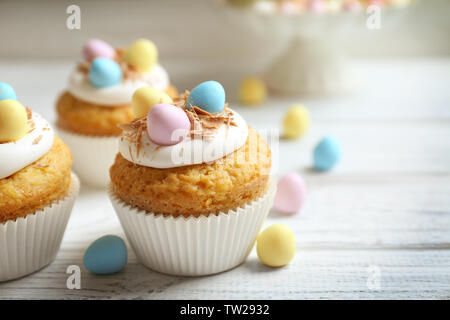 Tasty Easter cupcakes on white wooden table Stock Photo