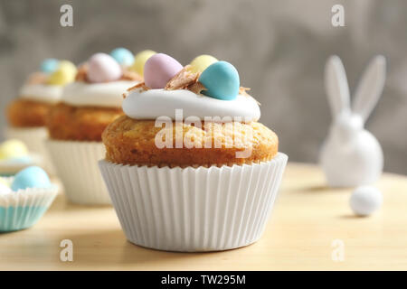 Decorated Easter cupcakes on wooden table against grey background Stock Photo