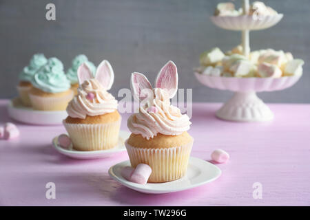 Tasty Easter cupcakes on pink wooden table against grey background Stock Photo