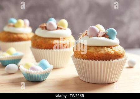 Decorated Easter cupcakes on wooden table against grey background Stock Photo