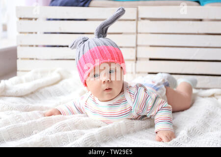 Cute little baby in bunny hat lying on soft blanket Stock Photo