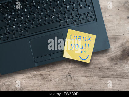 top view of words thank you written on sticky note on laptop computer Stock Photo