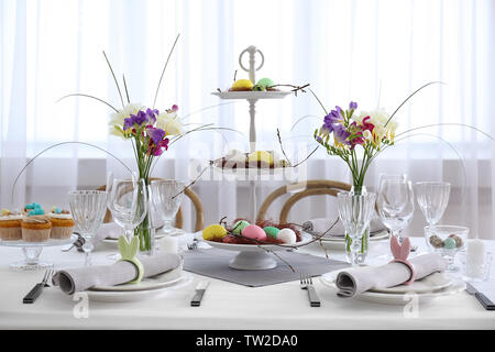 Beautiful Easter table setting in light room Stock Photo