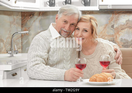 Cute elderly couple drinking wine in kitchen Stock Photo