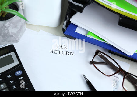 Paper with printed TAX RETURN text and stationery on table Stock Photo