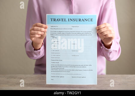 Woman sitting at table and showing blank travel insurance form Stock Photo
