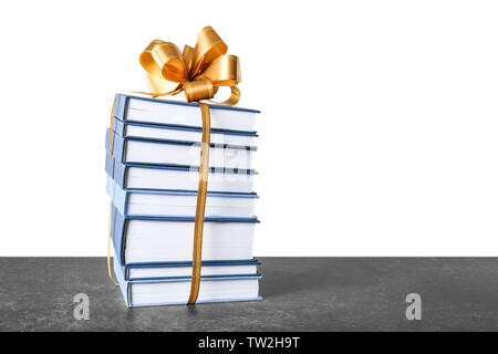 Stack of books with ribbon as gift on gray table Stock Photo