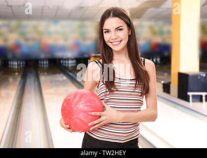 Beautiful young woman with ball in bowling club Stock Photo