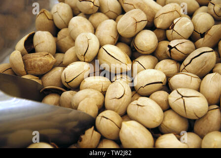 Ripe inshell pecans sold by weight in the market, selective focus,metal scoop, cracked shell Stock Photo
