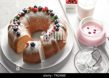 White plate with delicious sliced dessert and ingredients for yogurt cake on table Stock Photo