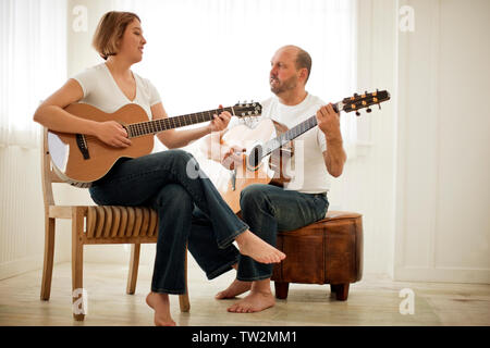 Woman teaching an older man how to play acoustic guitar Stock Photo