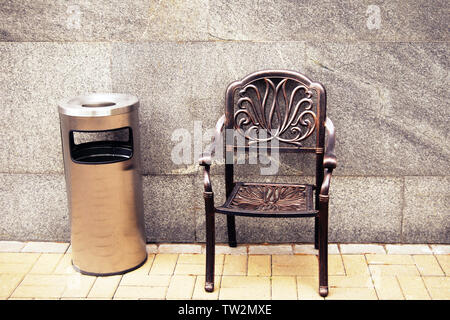 Smoking area, metal chair and outdoor trash can with ashtray against gray marble wall Stock Photo