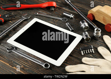 Tablet PC and tools for car repair on wooden table Stock Photo