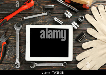 Tablet PC and tools for car repair on wooden table Stock Photo
