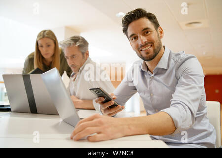 Startup team member smiling at camera in office Stock Photo