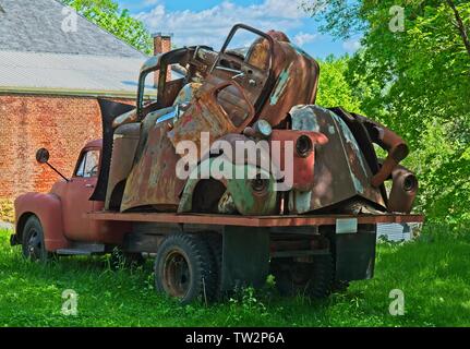 Vintage truck hauling old rusty car parts piled on the back parked in a empty lot Stock Photo