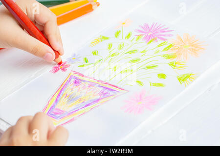 The child draws flowers for mom with pencils. Baby gift. White background. Stock Photo
