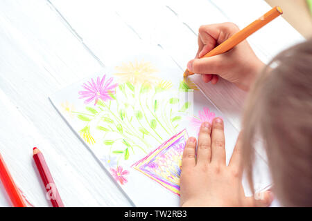 The child draws flowers for mom with pencils. Baby gift. White background. Stock Photo
