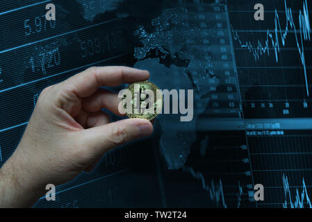 Human hand holding a golden virtual coin Bitcoin against a technological background. Global market concept with empty copy space for Editor's text. Stock Photo
