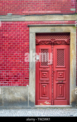 Ornate red door in a red tiled builing in Porto, Portugal. Stock Photo