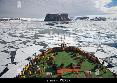 Tourists on Russian Icebreaker 50 Years of Victory approaching Rubini Rock, bird colony, Franz Josef Land, Russian Arctic. Stock Photo