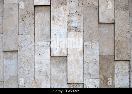 Natural stone wall of big vertical blocks of porous material in variety of beige tones. Stock Photo