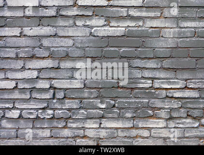 Uneven old brick wall gray painted with dark areas and white dapples, urban grunge background Stock Photo