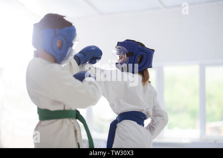 Boy and girl. Boy and girl wearing white kimono and protective helmets having fight studying martial arts Stock Photo