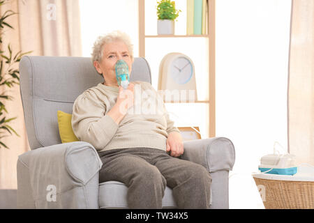 Elderly woman using asthma machine at home Stock Photo