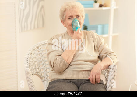 Elderly woman using asthma machine at home Stock Photo