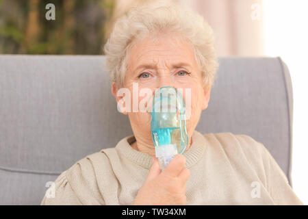 Elderly woman using asthma machine at home Stock Photo