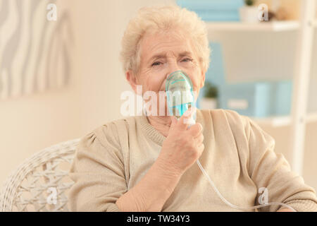Elderly woman using asthma machine at home Stock Photo