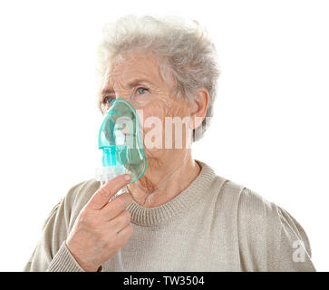 Elderly woman using asthma machine on white background Stock Photo