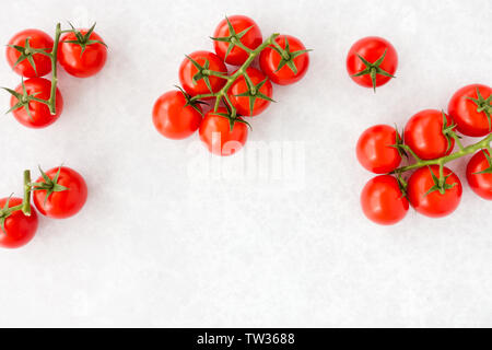 Tomatoes on the vine on gray textured and patterned background with copy space. Top view. Stock Photo