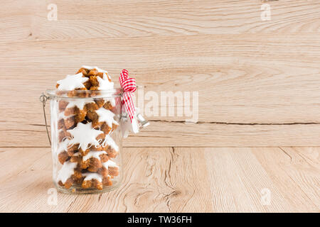Cinnamon Stars, Zimtsterne, German Christmas cookies in a glass jar with Christmas decoration on brown wooden background with lots of copy space. Low Stock Photo
