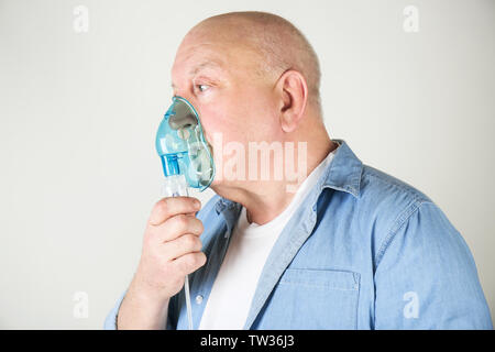 Senior man using asthma machine on light background Stock Photo