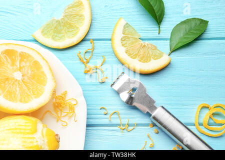 Composition with cut lemon, zest and special tool on wooden table, closeup Stock Photo