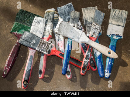 A pile of old, used paintbrushes with hard bristles and coated paint, ready to be thrown away. Stock Photo