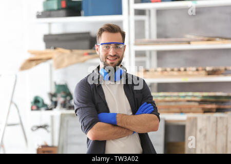 Young smiling carpenter standing with crossed hands in workshop Stock Photo