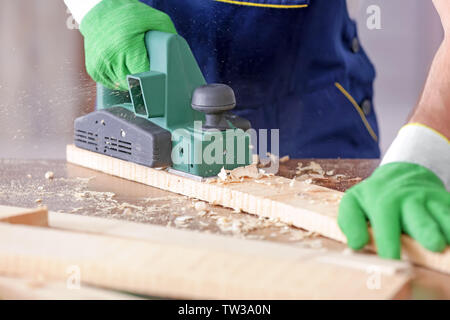 Carpenter working with electric plane, closeup Stock Photo