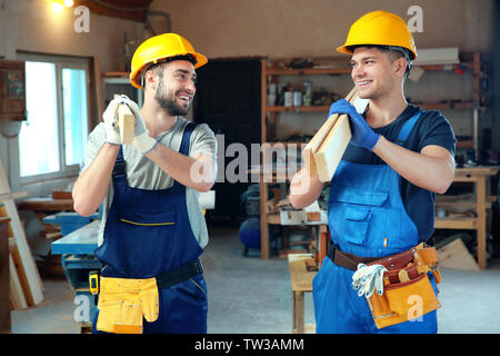 Two handsome young carpenters with boards in workshop Stock Photo