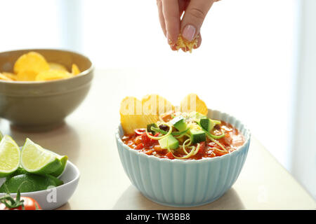 Female hand sprinkling grated cheese on chili turkey in ceramic bowl, closeup Stock Photo