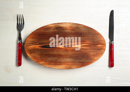 Wooden plate, fork and knife on table Stock Photo