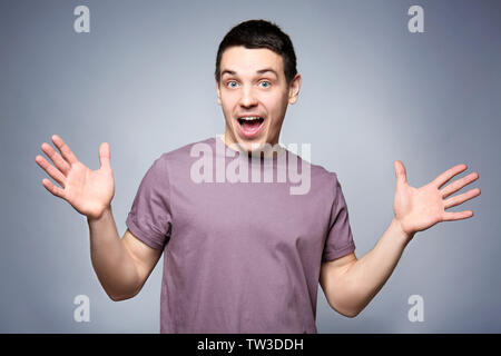 Handsome surprised young man on gray background Stock Photo