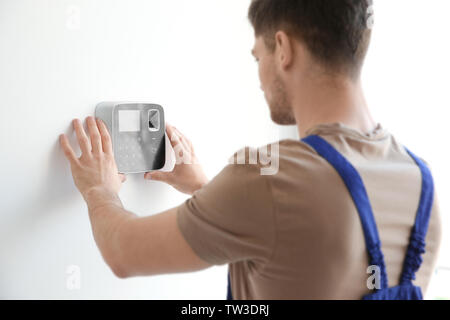 Young electrician installing security alarm on wall Stock Photo