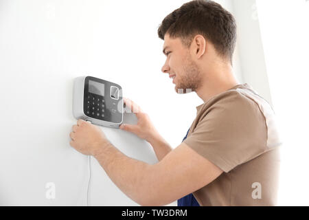 Young electrician installing security alarm on wall Stock Photo
