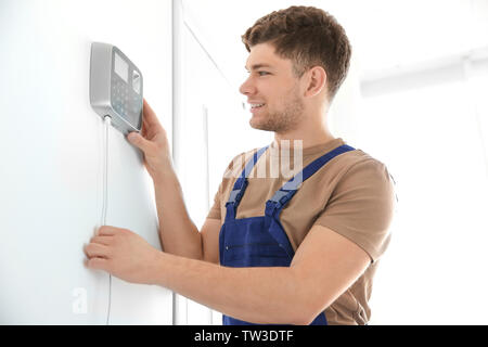 Young electrician installing security alarm on wall Stock Photo