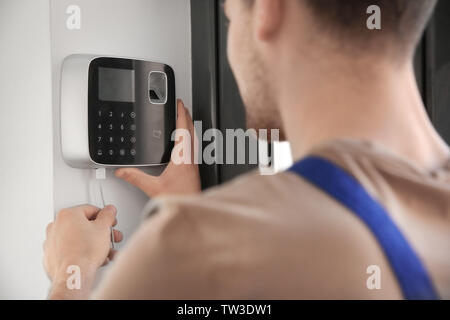 Young electrician installing security alarm on wall Stock Photo