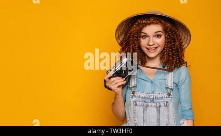 red haired funny tourist woman in chinese hat with photo camera smiling and very happy.Traveler teenager Stock Photo